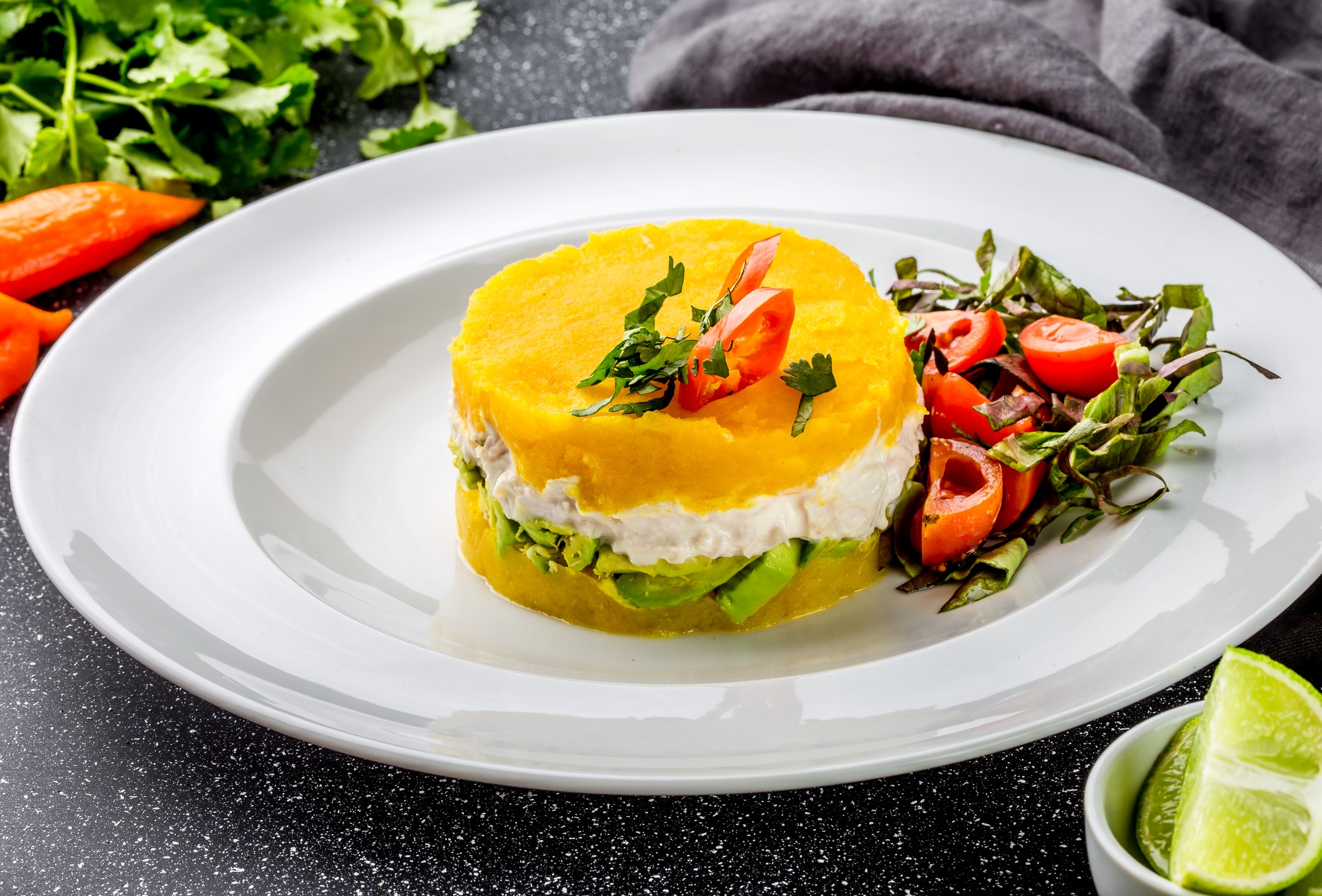 Traditional peruvian dish Cause from yellow potato, chicken, avocado on white plate.