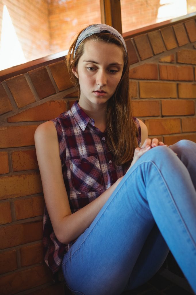 Sad schoolgirl sitting alone on staircase