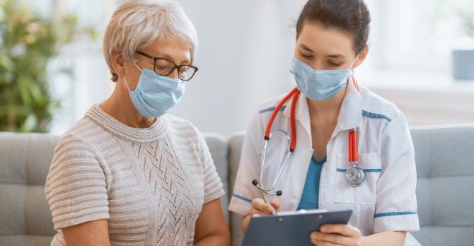 Doctor and senior woman wearing facemasks